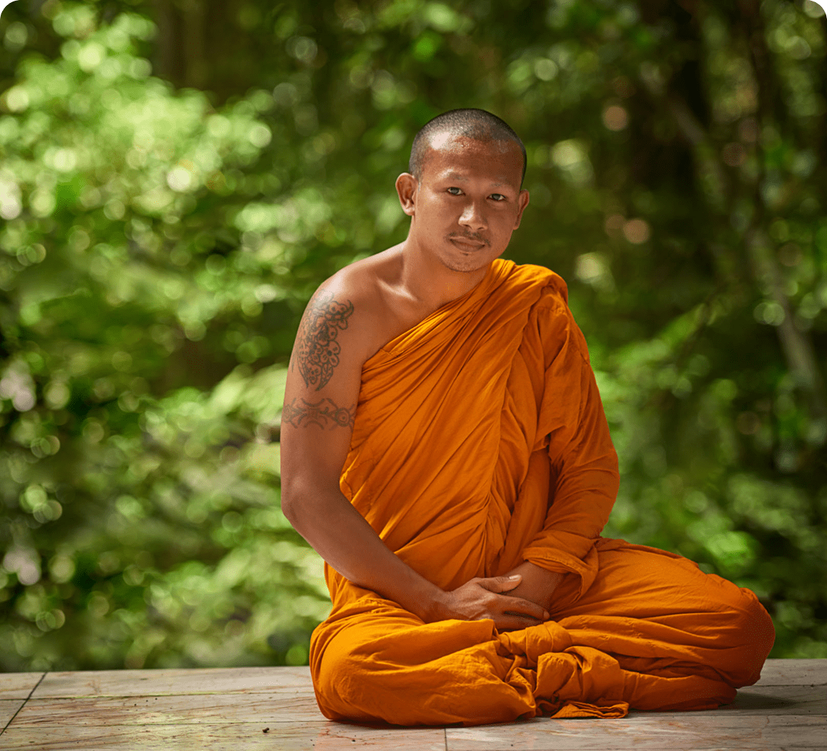 Monk meditating in peaceful forest setting.